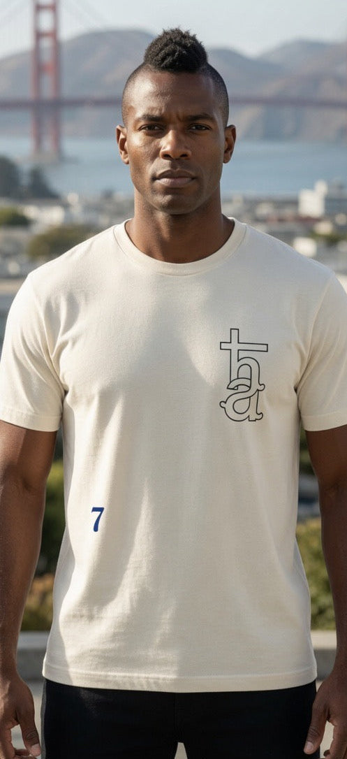 Cream graphic T-shirt with tall monogram and small blue number 7 on front