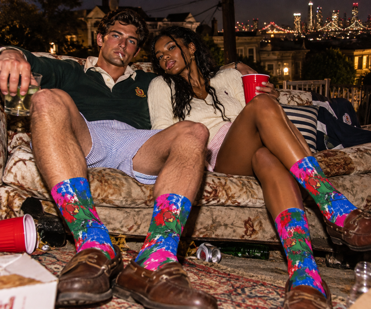 Crew socks with colorful tropical bird floral print, black toe and heel, on feet