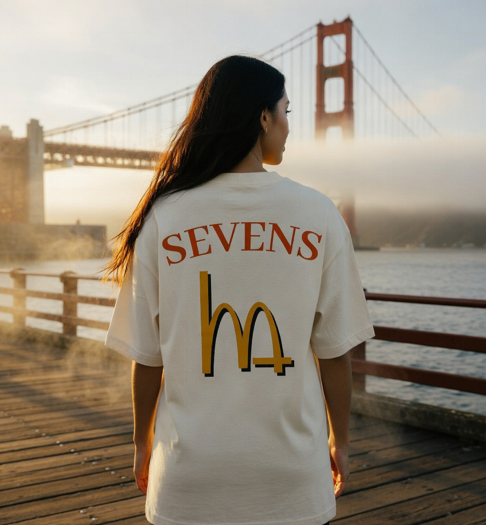 Cream tee with back 'SEVENS' text and large 'M+' logo graphic