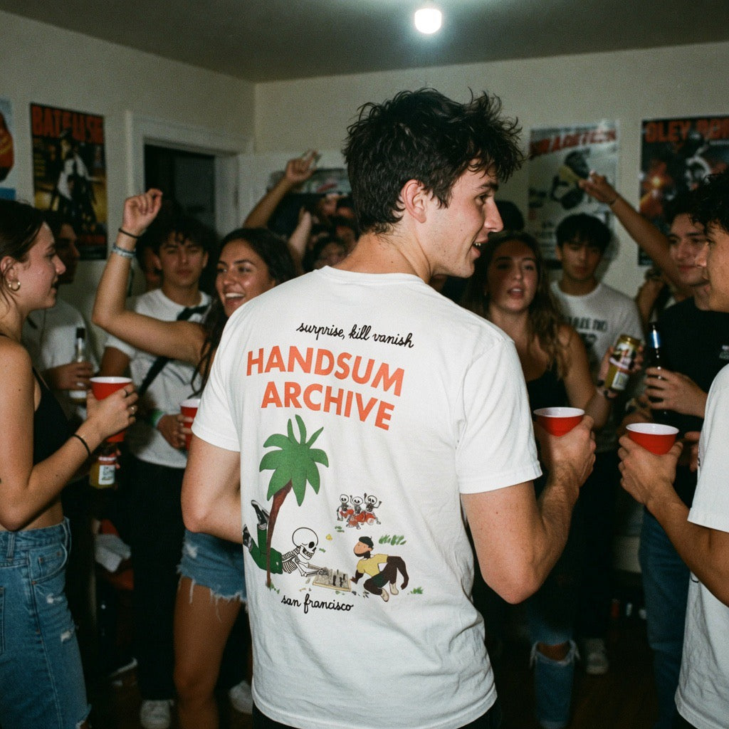 Handsum Island T-shirt, white crewneck with colorful back print “HANDSOM ARCHIVE” and palm graphic.